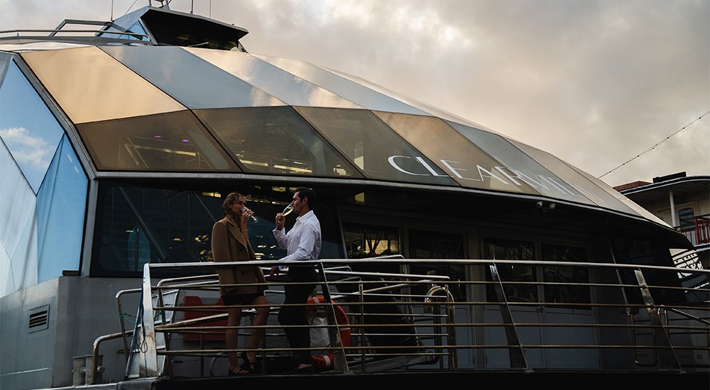 two people on a lunch cruise, enjoying a drink on one of the outer decks on the boat.