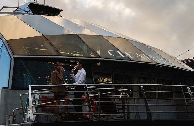 two people on a lunch cruise, enjoying a drink on one of the outer decks on the boat.