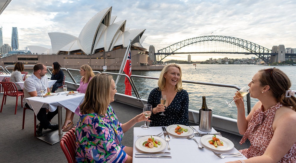Guests enjoying lunch on a Sydney Harbour cruise with Opera House and Harbour Bridge views